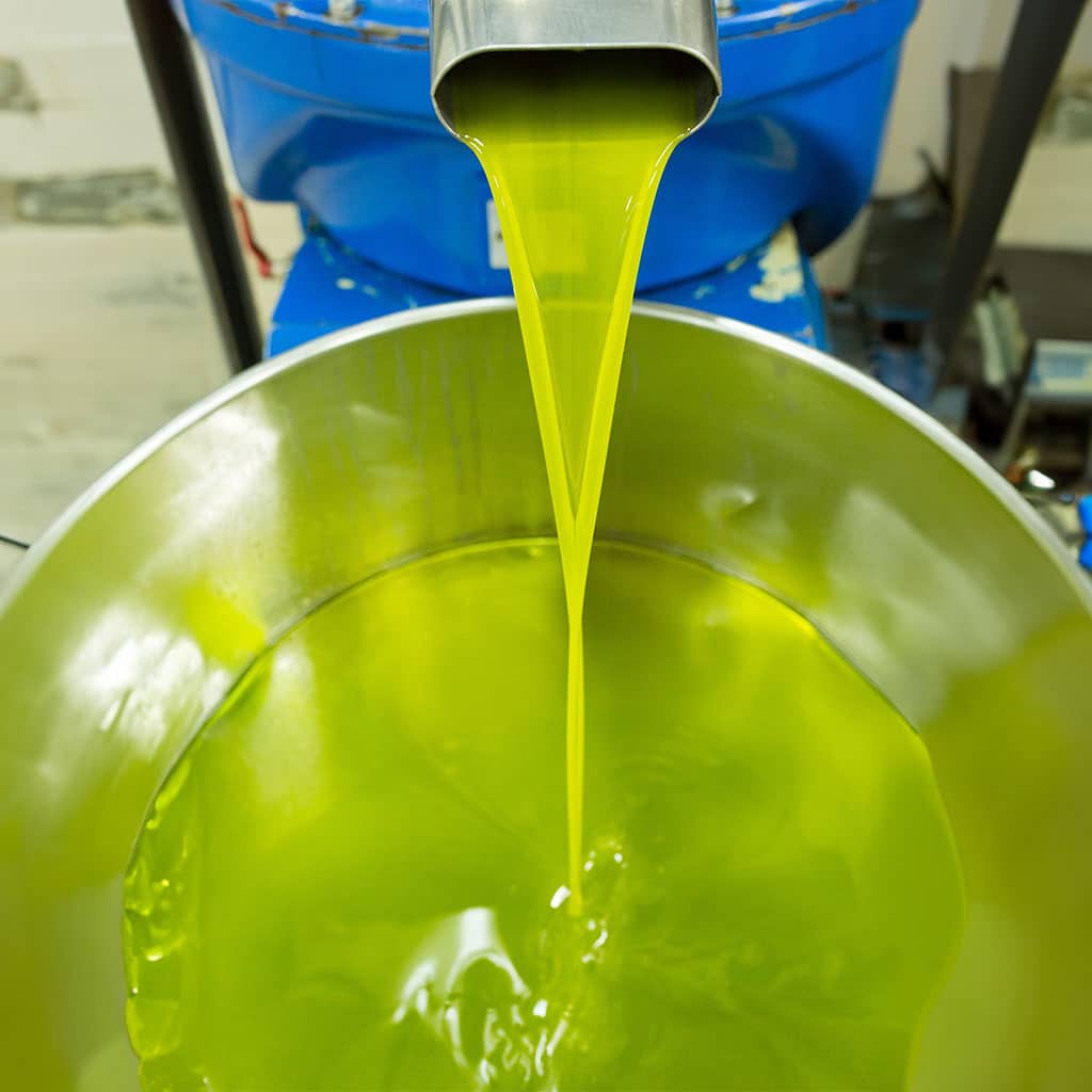 Olivenöl Pumpe, die frisches Öl in einem Gefäß pumpt