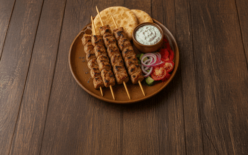 In der Mitte des Bildes sieht man das Gericht Souvlaki. Außerdem liegt noch auf dem Teller Pita und Tzatziki
