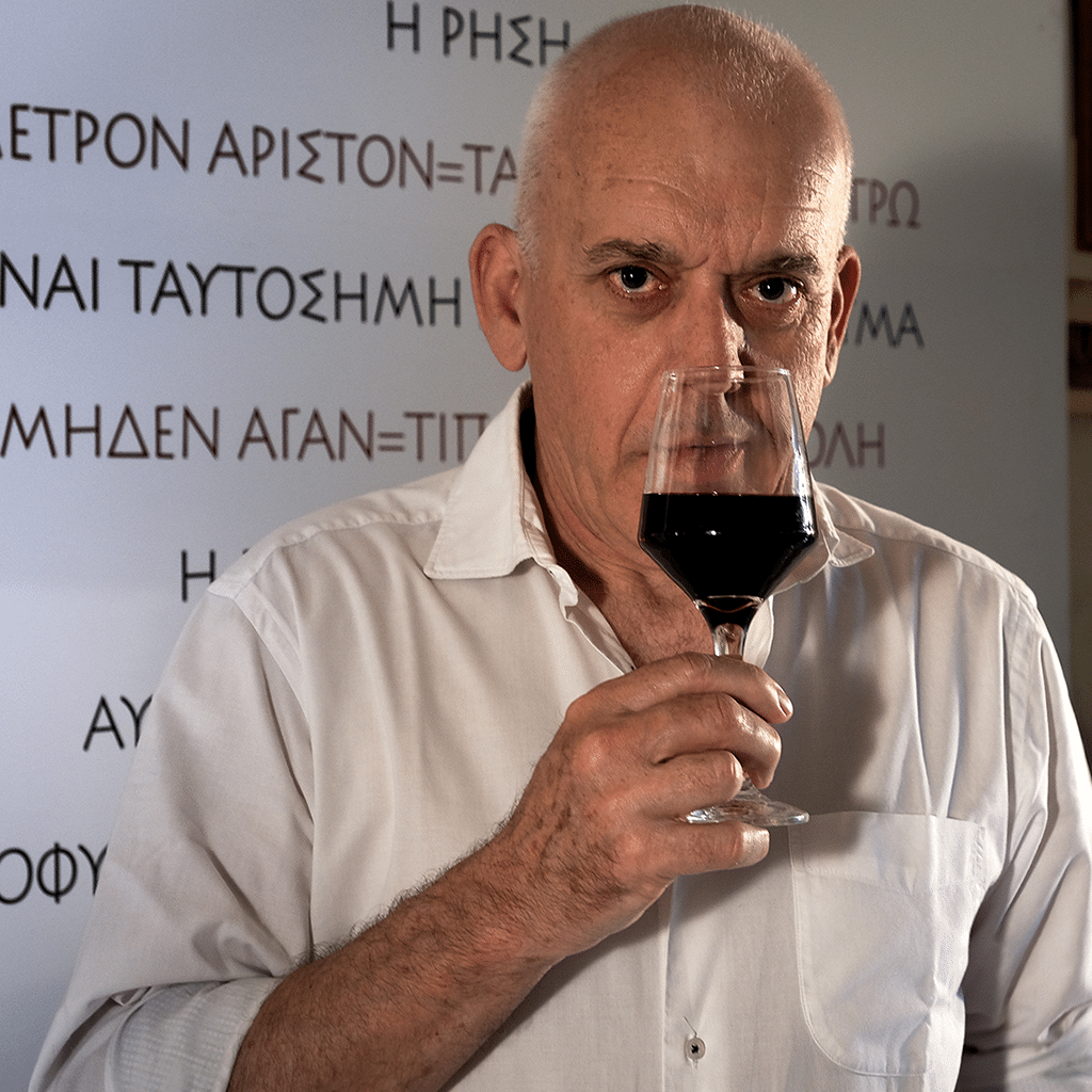der winzer papatoni richt den rotwein den er in der hand in einem glas hat